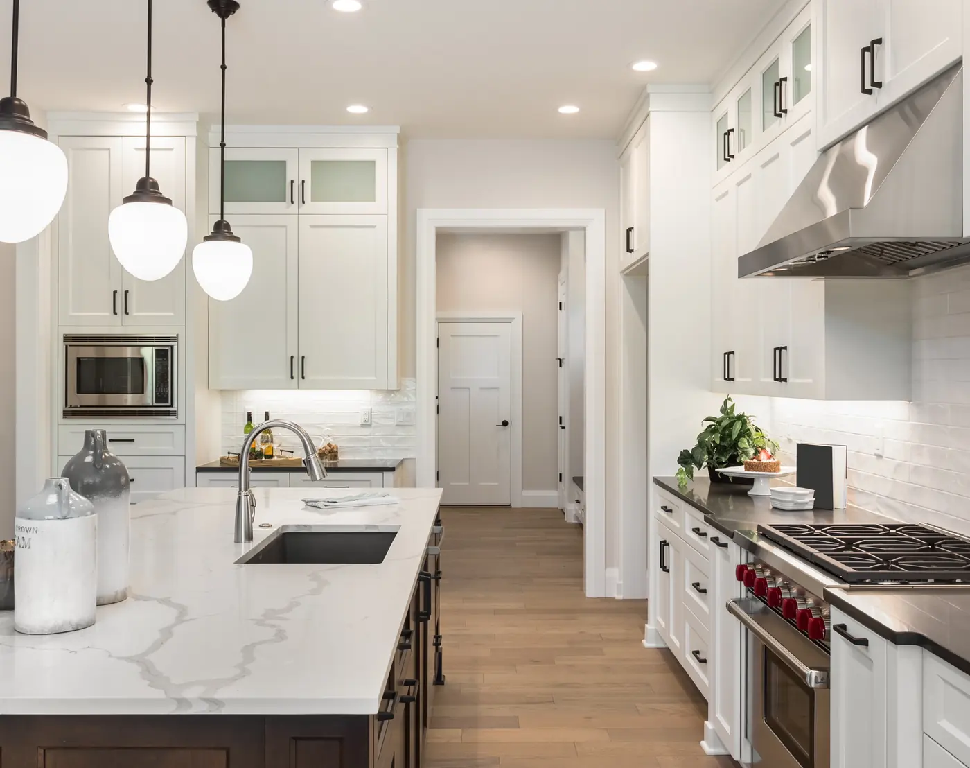 Renovated kitchen with marble counters, brass pendants and wood floors