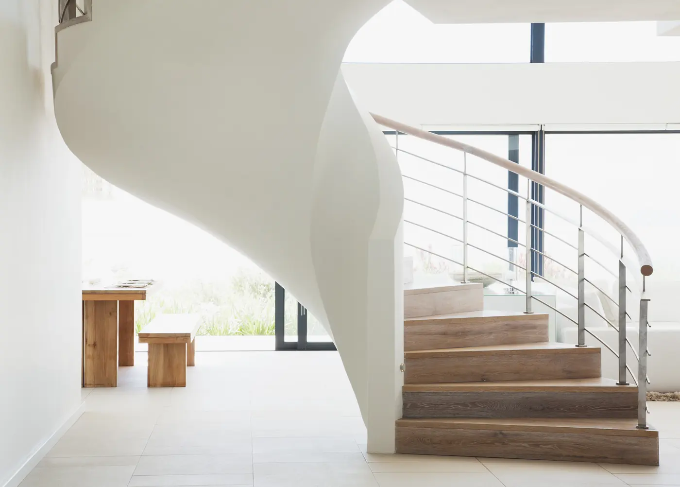 Sculptural white staircase with warm wood treads in a renovated home